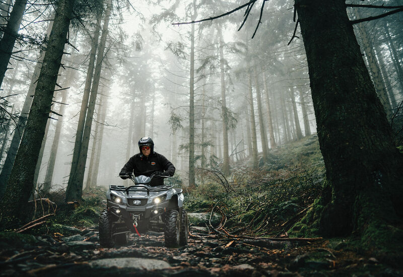 Man riding Argo Xplorer through a wet forest